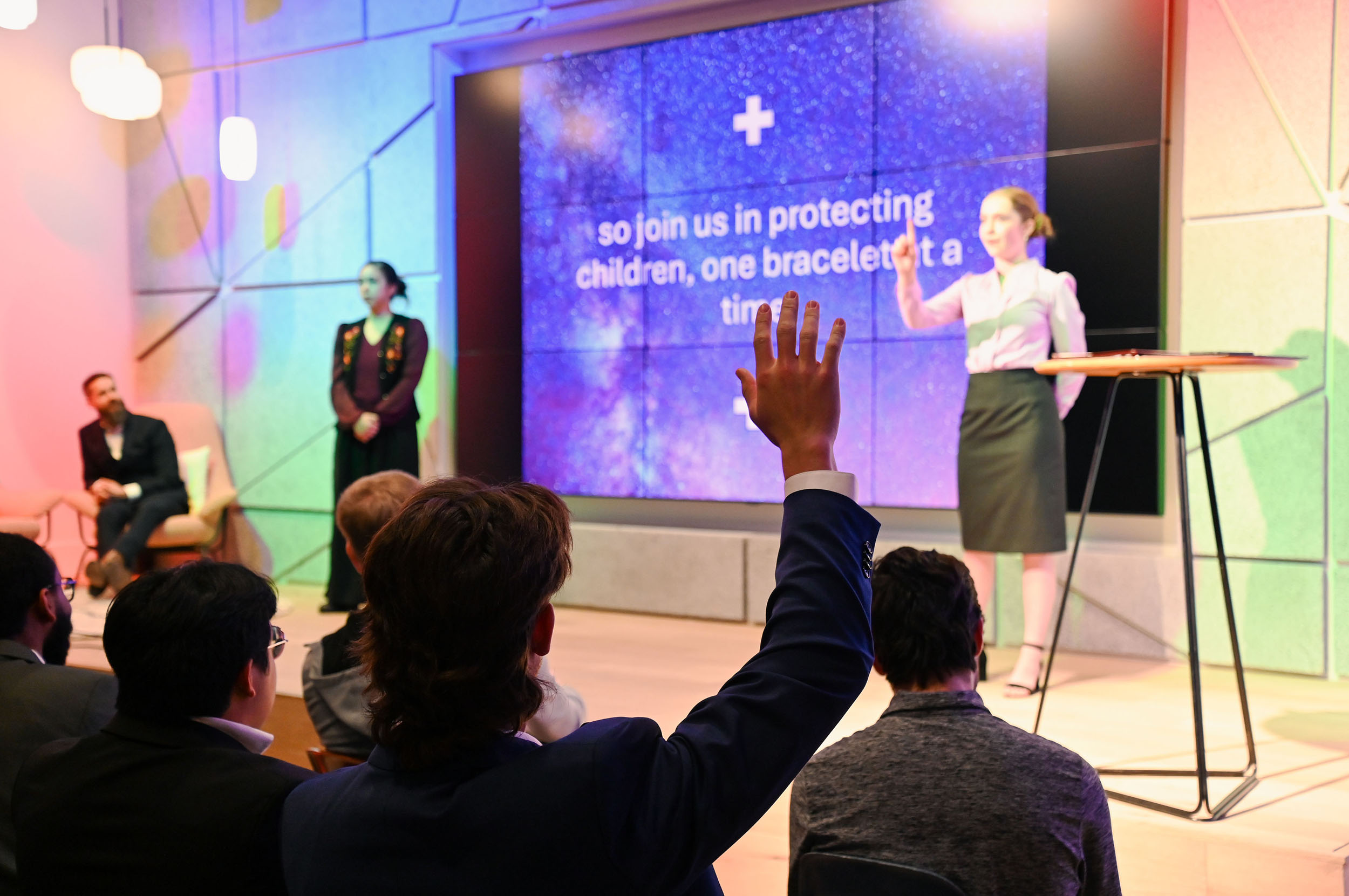 An entrepreneurship student raises his hand to ask a question during a business presentation